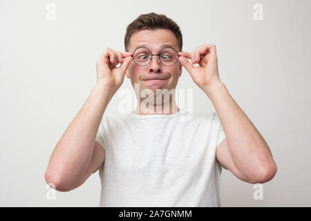 Giovane uomo europeo in bicchieri guardando sul naso. Problema con la vista squinted. Studio shot Foto Stock