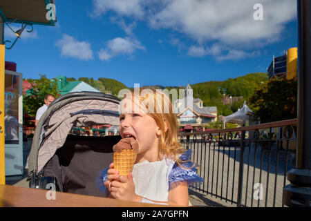 Bambina grande mangia il gelato nel parco. Ritratto di profilo con il fuoco selettivo. Viaggi in Canada. Foto Stock