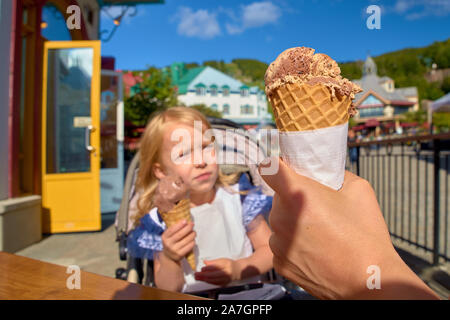 Bambina grande mangia il gelato nel parco. Ritratto di profilo con il fuoco selettivo. Viaggi in Canada. Foto Stock