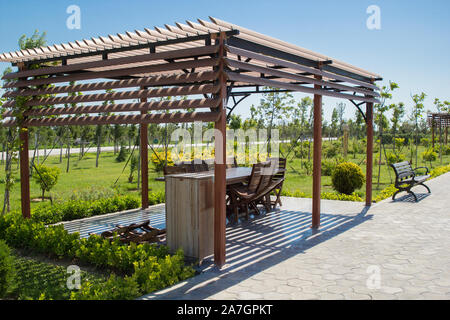 Pergola in legno nel parco primaverile con mobili da giardino in legno Foto Stock
