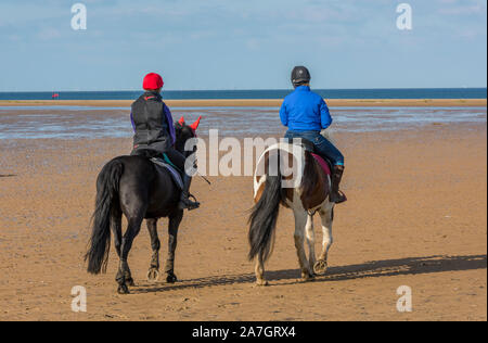 Due piloti del Cavallino fantini o sulla spiaggia di holkham sulla Costa North Norfolk equitazione sulla sabbia. Foto Stock