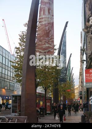 Foto di vetrine, autobus, alberi di alto fusto, pedoni e Titanic banner su Donegall Place, una delle principali strade dello shopping nel centro di Belfast. Foto Stock
