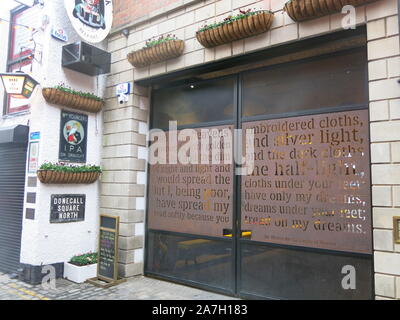 Un poema di W B Yeats è parte dell'arte di strada che adorna gli edifici a Belfast il Tribunale commerciale di ciottoli un vicoletto pieno di nostalgia irlandese. Foto Stock