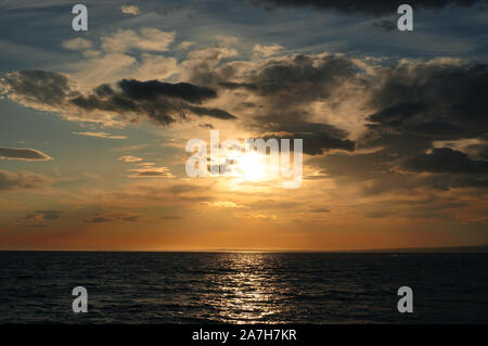 Arancione tramonto sul mare calmo blue sky nuvole pesanti Foto Stock