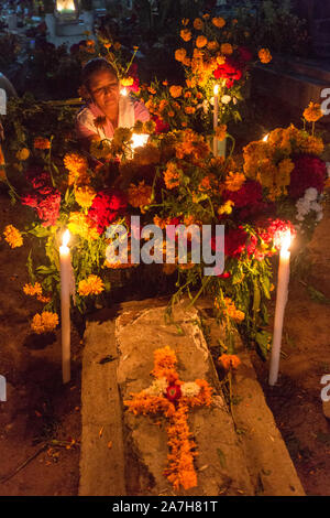 Una donna messicana candele luci presso il recinto di parenti per il Giorno dei Morti festival noto in spagnolo come Día de Muertos al vecchio cimitero Ottobre 31, 2013 in Xoxocotlan, Messico. Il festival celebra la vita di coloro che sono morti. Foto Stock