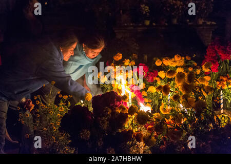 I membri della famiglia accendono le candele in onore del morto a San Felipe de Aqua cimitero durante il Giorno dei Morti Festival noto in spagnolo come Día de Muertos il 2 novembre 2013 a Oaxaca, Messico. Foto Stock