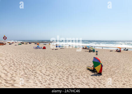 Vista in spiaggia con le persone facendo bagni di sole sulla spiaggia. Oceano atlantico, Costa Nova, Portogallo Foto Stock