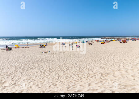 Vista in spiaggia con le persone facendo bagni di sole sulla spiaggia. Oceano atlantico, Costa Nova, Portogallo Foto Stock