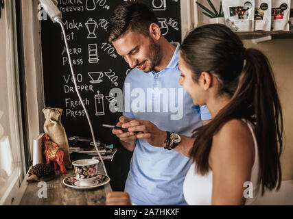 Coppia caucasica poggiante sulla caffetteria e spendere il loro tempo insieme a tazze di caffè Foto Stock