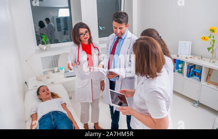 Il gruppo di medici in piedi accanto a un malato e discutere le cause per la sua malattia. Foto Stock