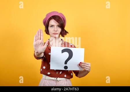 Giovane donna caucasica tenendo la carta con il punto interrogativo con mano aperta Foto Stock