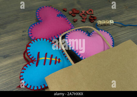 Sacchetto di carta pieno di cuore a mano souvenir e lettere di amore su legno rustico sfondo. Amore, relazione, il giorno di San Valentino, acquisto di concetto di amore Foto Stock