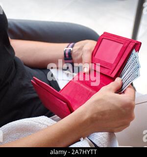 Sezione mediana della giovane donna pagando bill nel ristorante. Red wallet con dollari Foto Stock