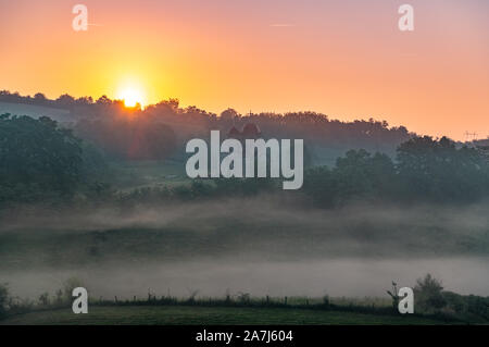 Bellissima la mattina presto landskape da una nebbia strada da qualche parte in Serbia,con qualche santo sacramento in una distanza Foto Stock