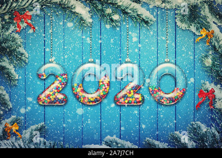 Felice Anno Nuovo 2020 holiday sfondo. Set di numeri trasparente fatta di vetro riempito con multicolore di caramelle e dolci appendere sul Natale nevoso tre Foto Stock