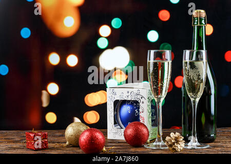 Champagne in bicchieri e in una bottiglia. Natale romantico sfondo. Nelle vicinanze si trova un giocattolo di Natale. luogo per il testo Foto Stock