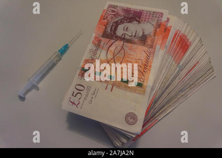 Foto di denaro siringa spacciatore di droga. Dipendenza da eroina. GBP soldi bill close up, spacciatore concept Foto Stock
