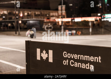 VANCOUVER, BC, Canada - Ott 05, 2019: un uomo senza tetto con un carrello, fuori fuoco, passando da un governo del Canada, oggetto della messa a fuoco e federale Foto Stock