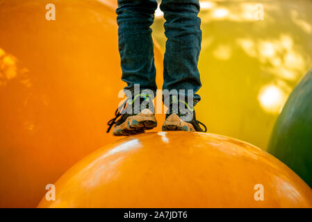 Baby, ragazzo salta su enormi sfere. Gambe fotografato da dietro. Sfere gialle. Foto Stock
