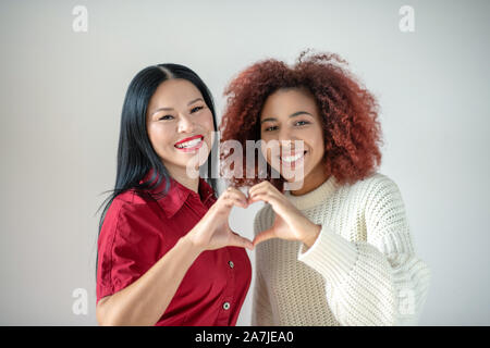 Donna asiatica con labbra rosse in piedi vicino ai suoi migliori amici Foto Stock