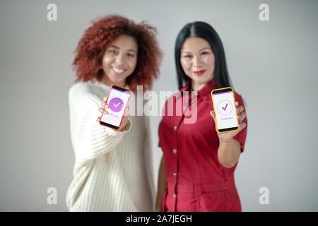 Gli amici gli smartphone di contenimento durante l'utilizzo di social media Foto Stock