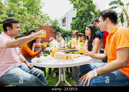 Un folto gruppo di famiglie felici di mangiare la colazione del mattino insieme in giardino home Foto Stock