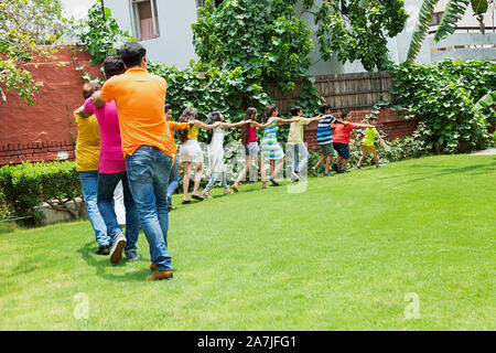 Gruppo di Felice grandi famiglie camminare insieme in treno la formazione di fronte al-la loro casa in giardino Foto Stock