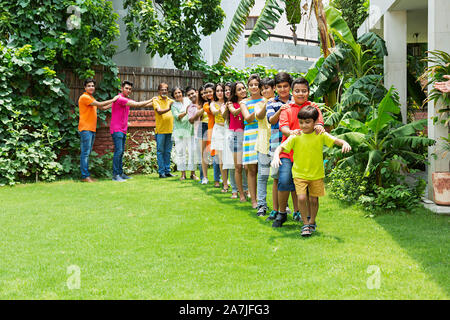 Gruppo di Felice Multi-generazione Famiglia camminare insieme in treno la formazione in-parco del-la loro casa Foto Stock