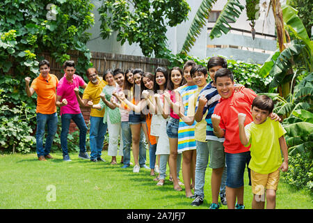 Un gruppo di grandi famiglie Stati in piedi in una linea di prodotti insieme e con le mani vincenti del pugno di celebrazione di successo nel giardino di casa Foto Stock