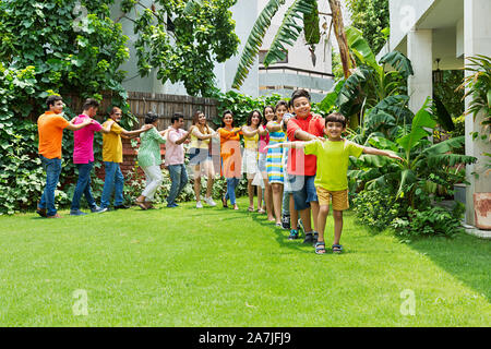 Grande gruppo di famiglia indiana dei soci del camminare in-a-linea insieme Having-Fun godere nel parco della loro casa Foto Stock