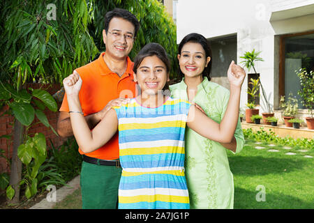 Happy-Family genitori adulti e ragazza adolescente insieme Fists-Hand conquistando il successo celebrazione in cortile vicino a casa loro Foto Stock