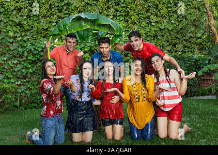 Group-Of adulto felice maschio e femmina amici divertendosi godere in The-Rain in-outdoor presso-park Foto Stock