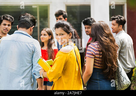 Il gruppo di college di giovani ragazzi e ragazze studenti compagni di classe standing In-Outside College Campus Universitario Foto Stock