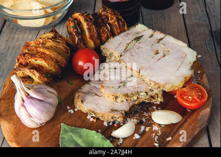 Un pezzo di cosse al forno ripiene di carne con patate e verdure in una padella e una tavola di legno. Foto Stock