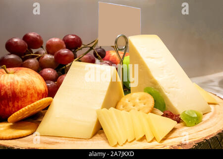 Formaggio gruviera con varietà di frutta e cracker sul piatto di legno in linea a buffet Foto Stock