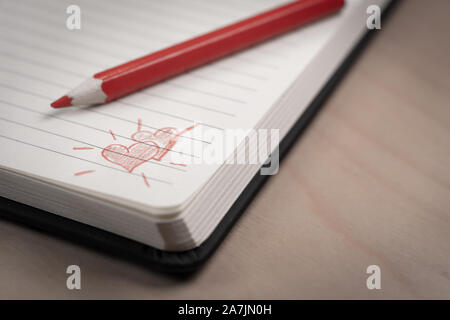 Amore cuori su notebook con la penna su un tavolo di legno Foto Stock