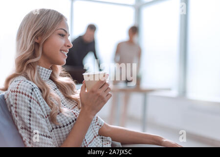 Giovane donna di affari con una tazza di caffè in un ufficio moderno Foto Stock