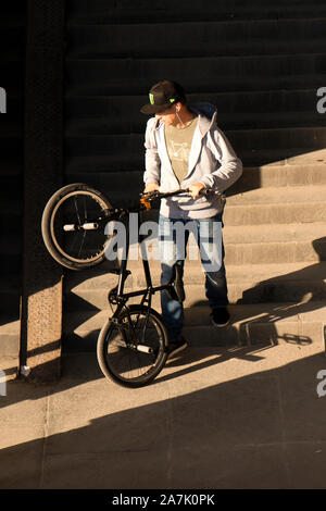 A Belgrado, in Serbia - Ottobre 25, 2019: Un uomo spingendo la bici acrobatica giù il pubblico scale di luce e ombre Foto Stock