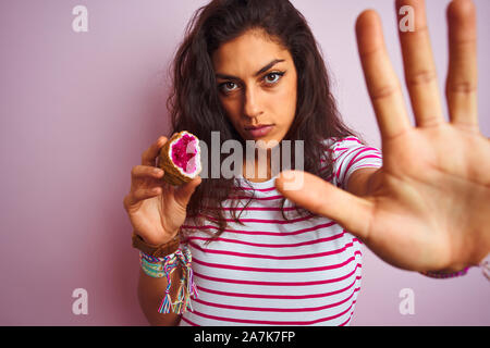 Giovane donna bellissima azienda ametista gemma isolata su sfondo rosa con mano aperta facendo segno di stop con gravi e fiducioso di espressione, de Foto Stock