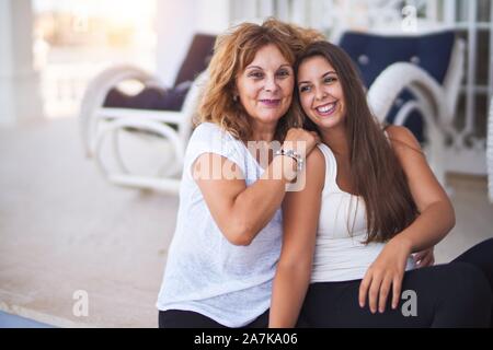 Bella madre e figlia seduti in terrazza abbraccia e sorridente Foto Stock