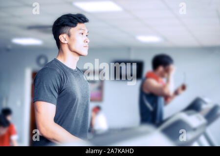 Giovani asiatici atheletic uomo in sportswear camminando sul tapis roulant in palestra Foto Stock