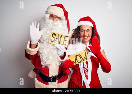 Paio di indossare il costume di Santa holding wow e la vendita di banner isolato su sfondo bianco rinuncia a dire ciao felice e sorridente e cordiale benvenuto gestu Foto Stock