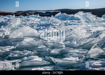 Un sacco di sottili e taglienti di lastre di ghiaccio in una grande pila di neve sul lago Baikal. Soleggiato, cielo chiaro. Messa a terra dietro la neve hummocks. Foto Stock