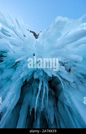 Blue Lunghi ghiaccioli appesi da la grotta degli archi. Inverno stalattiti. Copia dello spazio nel cielo blu. Orientamento verticale. Foto Stock