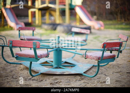 Parco giochi per bambini con una vecchia giostra nella sabbia. Foto Stock