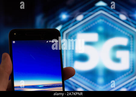 Uomo con lo smartphone. 5G touch screen pulsante inteface sullo sfondo, Los Angeles, California - 25.10.2019 Foto Stock