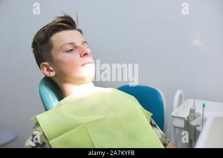 Ragazzo adolescente seduto in poltrona odontoiatrica presso la clinica Foto Stock