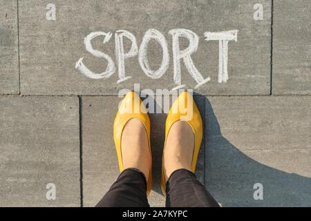 Sport di parola scritta sul marciapiede grigio con gambe di donna, vista da sopra Foto Stock