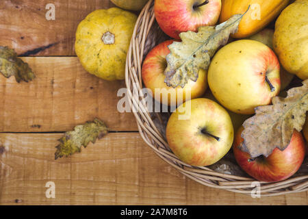 Fresche mele biologiche e zucche in un cesto su un tavolo di legno, vista dall'alto con copia spazio. Nutrizione sana nozione. Foto Stock