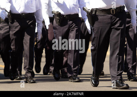 Close up di forze di polizia di sesso maschile, indossando blu scuro pantaloni e camicia bianca a una sfilata Foto Stock